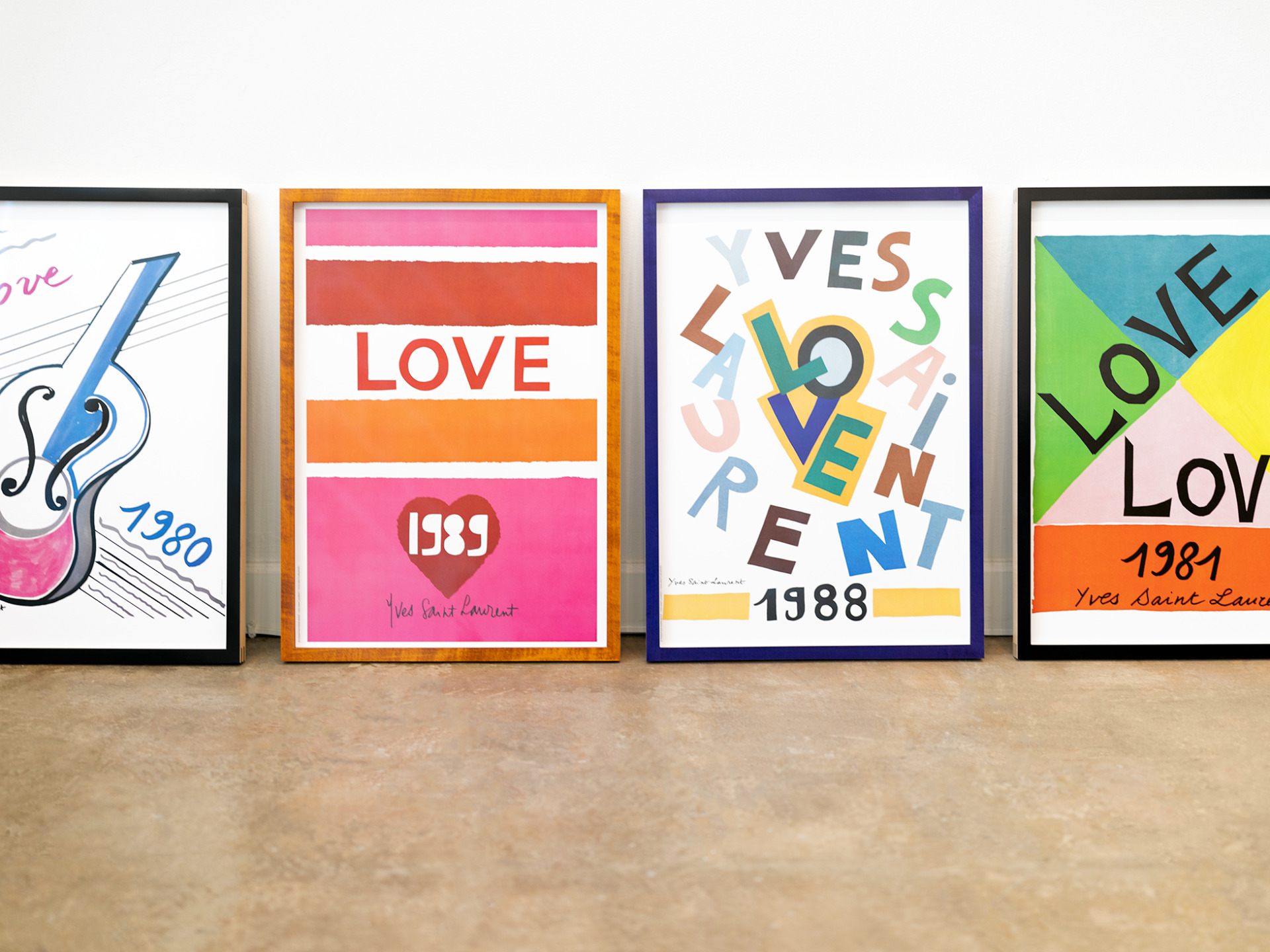 A series of vintage 1980's Yves Saint Laurent posters custom framed in colorful stained maple wood frames.